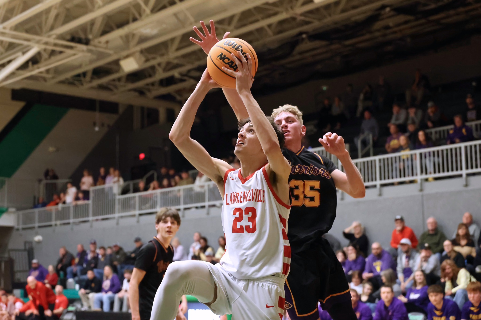 Lawrenceville's Noah Wilson (23) goes up for a shot as Jackson High of Casey-Westfield goes for the block from behind during an IHSA Class 1A Sectional basketball game in Macon (photo by Dave Rohr).